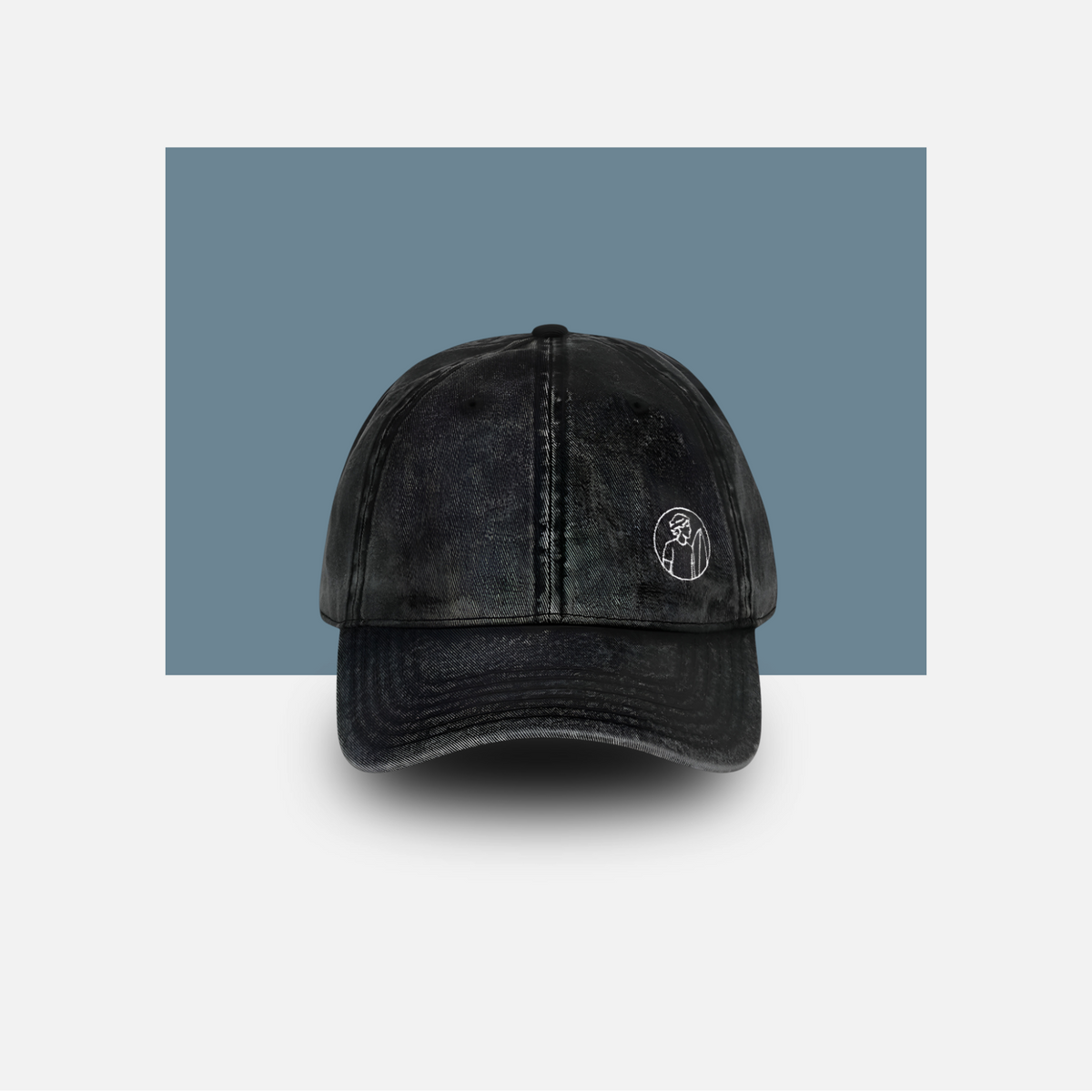 Black distressed baseball cap with a logo on a light gray background