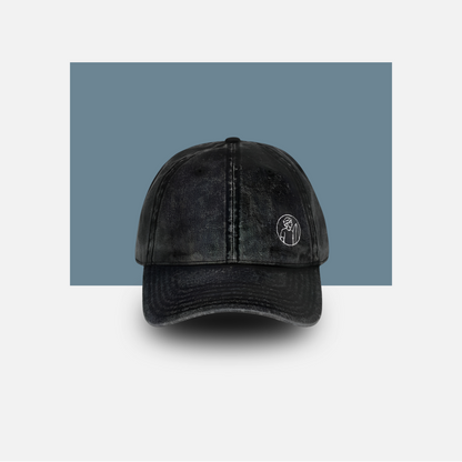 Black distressed baseball cap with a logo on a light gray background